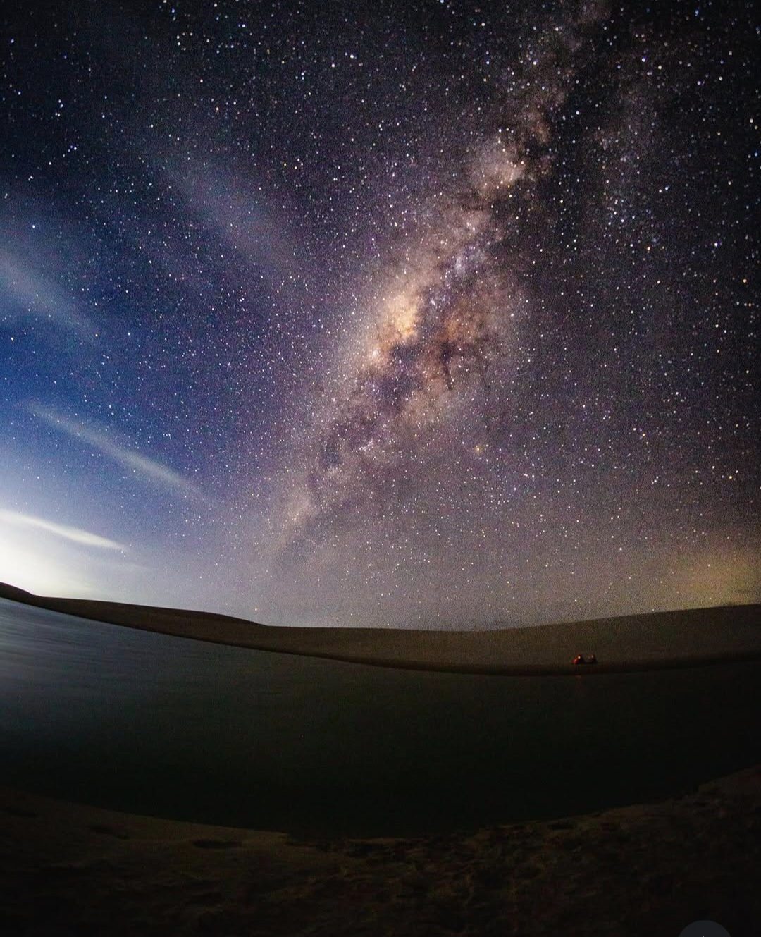 A Via Láctea atravessando o céu sobre uma lagoa dos Lençóis, refletida na água