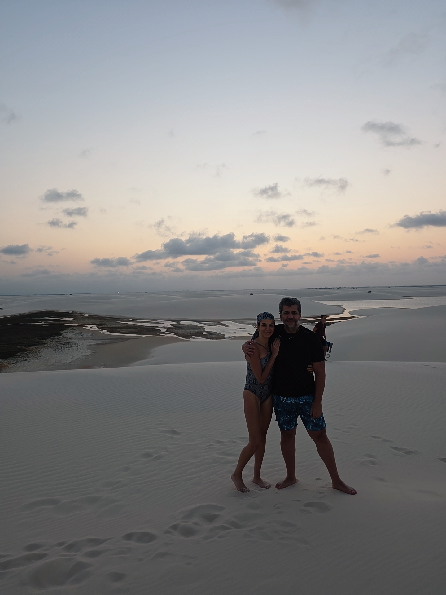 Eu e Sabrina no alto de uma duna ao anoitecer, com lagoas e dunas ao fundo