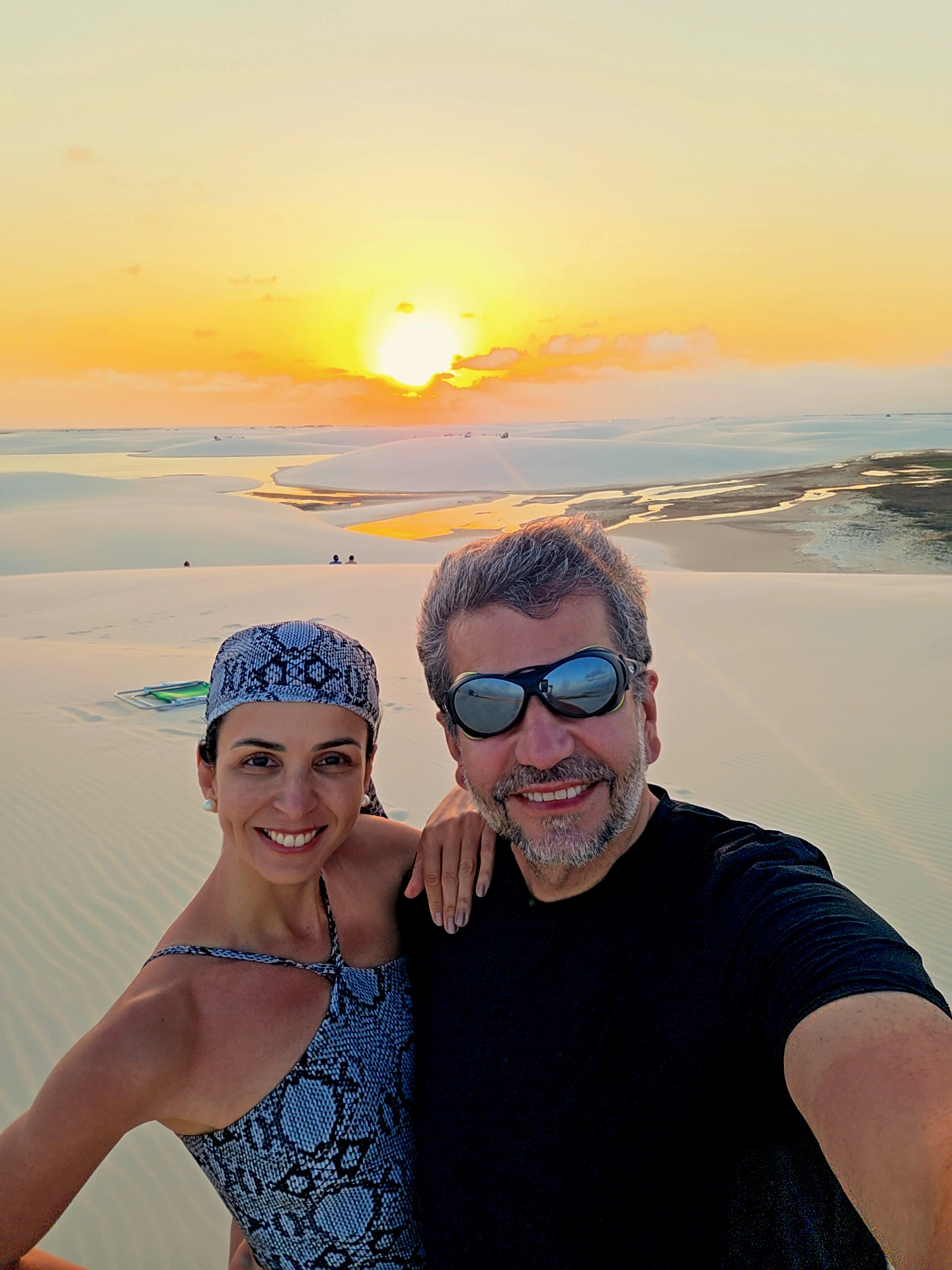 Eu e Sabrina abraçados no alto de uma duna, o sol se pondo sobre as lagoas