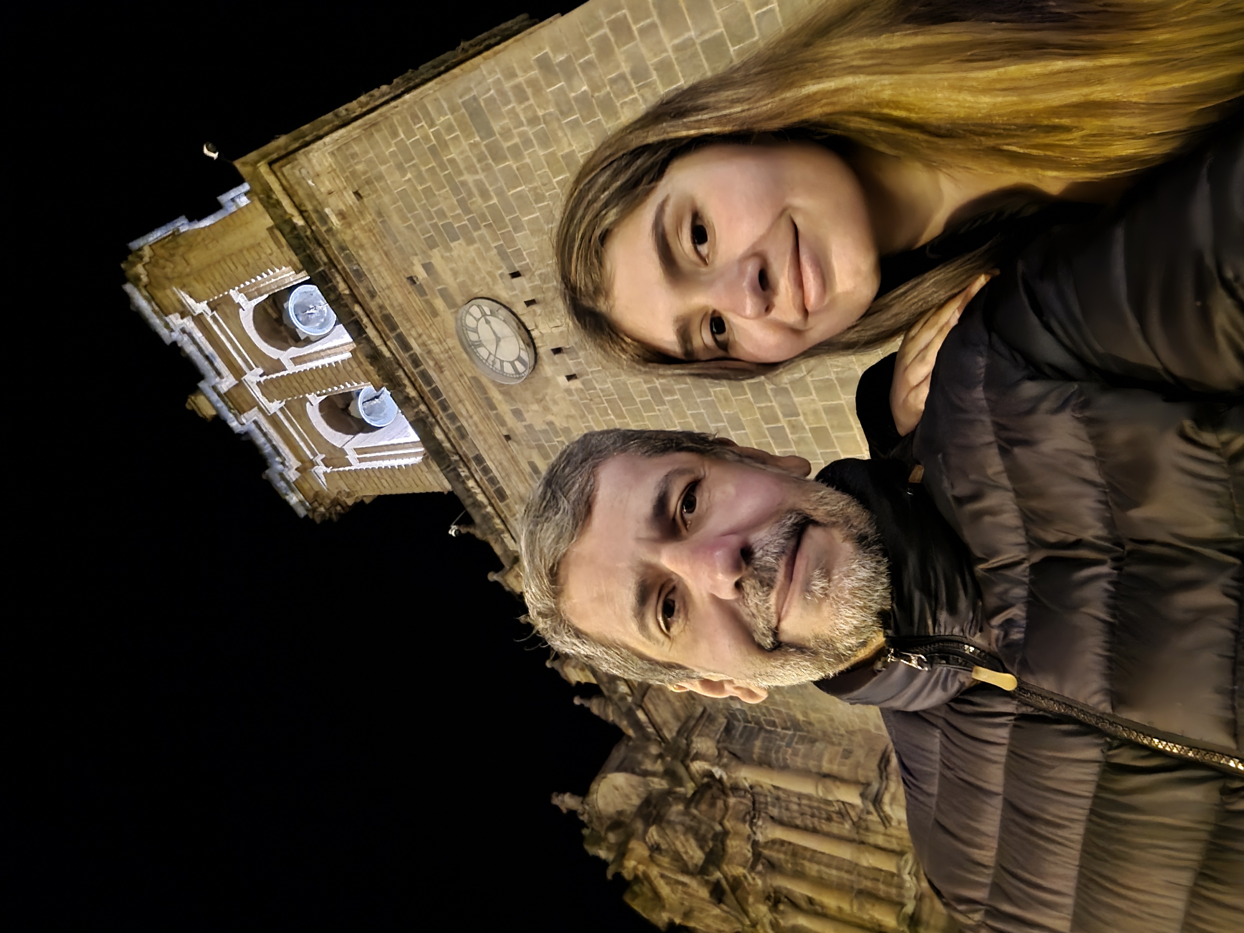 Nós dois na praça, com a torre do relógio da catedral atrás
